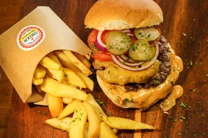 Cheekin burger with cheese, pickles and a bag of chips
